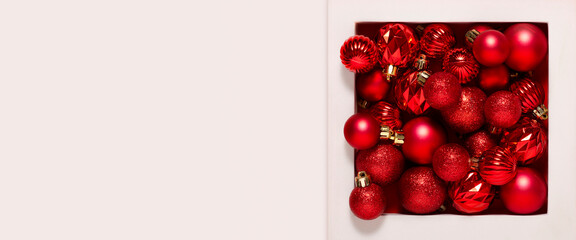 Red decorative balls in a white square pedestal on a white background. Banner.