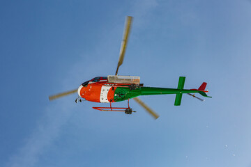 Fototapeta na wymiar near TARVISIO, FRIULI-VENEZIA GIULIA, ITALY - february, 2021: Mountain rescue helicopter painted in the colors of the italian flag flying in the blue sky
