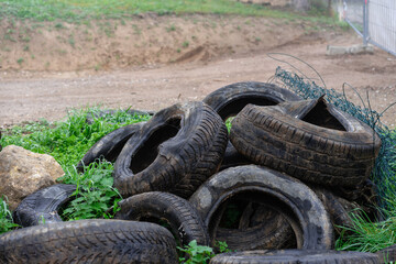 Tires in the grass, used car tires are thrown on a vacant lot, Grain effect, selective focus