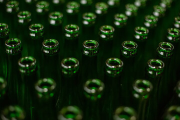 Glass factory, industrial production of glass containers. A lot of empty glass bottles as a background of green glass containers with copy space. Bottles for drinks. Technological work at the factory.