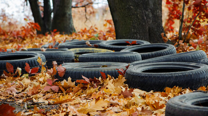 garbage from a heap of black old car tires among the trees in nature. environmental pollution....
