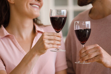 Close up happy loving affectionate couple man woman clinking glasses of red wine, enjoying romantic date, celebrating wedding anniversary or special occasion together at home, relations concept.