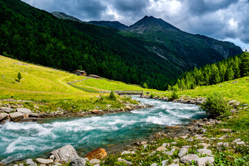 Fototapeta na wymiar Picturesque Alpine Landscape With Old Farmhouse And Clear River In Deferegental In Tirol In Austria