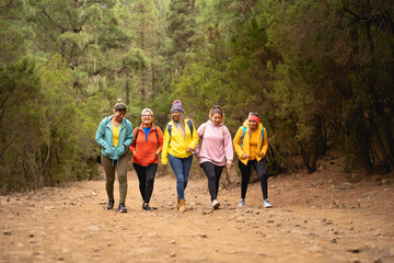 Group of women with different ages and ethnicities having fun walking in the woods - Adventure and...