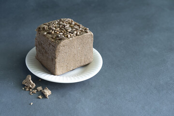 halva from sunflower seeds on a white plate with seeds, on a gray background. National traditional Turkish halva . High quality photo