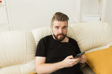 Handsome hipster man using cellphone at home. Communication leisure and technologies concept