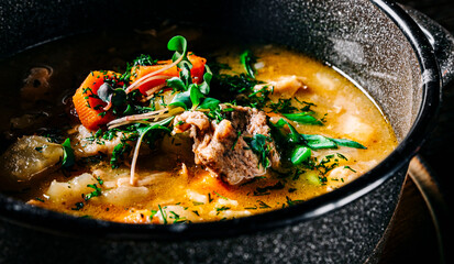 meat soup with vegetables in bowl on wooden table background