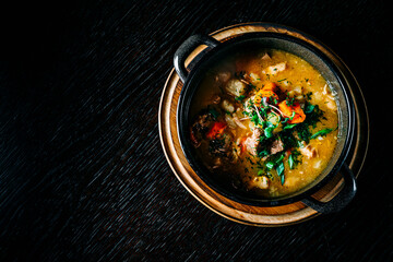 meat soup with vegetables in bowl on wooden table background
