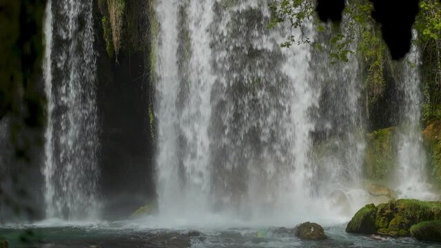 slow motion of Upper Duden Waterfall in Antalya, Turkey. grandiose powerful streams of water flows fron high steep cliff in big cave