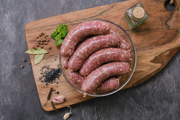Freshly made raw sausages mix in skins with herbs in a glass bowl. Raw homemade bratwurst sausages...