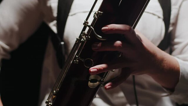 Closeup fingers of musician playing classical music on bassoon in studio. Musicians performs musical composition on bassoon