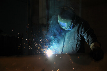 Electric welder at work. A worker welds metal structures at a factory.