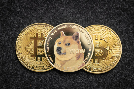Dogecoin cryptocurrency physical coin laying on top of two bitcoin coins