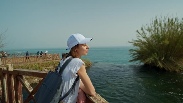 slow motion portrait beautiful woman tourist standing at edge of observation deck on Lower Duden Waterfall background in Antalya. Famous view point on mediterranean sea coast in Turkey.