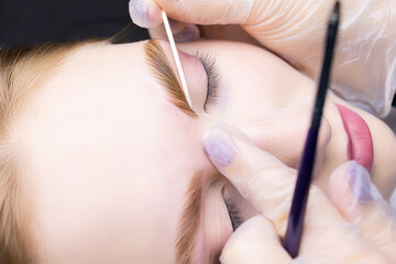 close-up alignment of the contour of the eyebrows with a cotton swab after the procedure lamination...