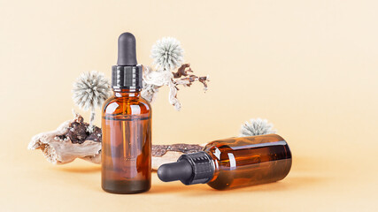 Fototapeta premium Essential oil in glass dropper bottles on a neutral beige background. Aromatherapy, massage oil, natural organic cosmetic, alternative medicine. Front view, copy space.
