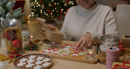 Asia woman happy enjoy fun make craft gift for X'mas night party sweet snack cooking recipe on table in good warm relax time. Cute smile gingerman bakery icing sugar glaze with red green white color.
