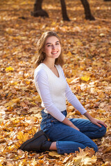  Portrait of a young girl in blue jeans posing in an autumn park