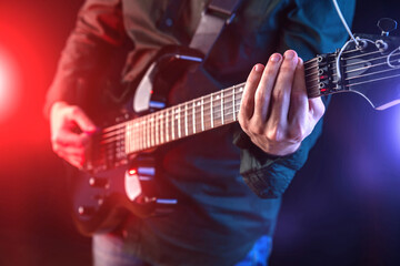 Obraz na płótnie Canvas Male hands playing electric guitar. Musician man with black guitar at a rock concert