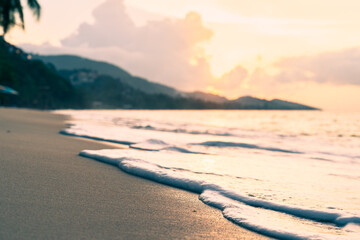 Sea surf on a sandy beach against the backdrop of a colorful sunset