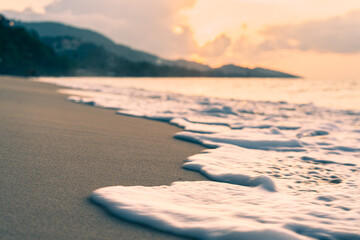 Sea surf on a sandy beach against the backdrop of a colorful sunset