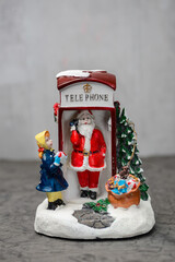 christmas toy santa claus in a red telephone booth with a christmas tree vertical photo
