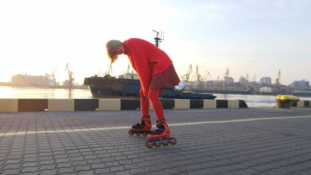 Stylish teenage girl rollerskating at sunrise, urban sports, fun leisure activity in sea port, teenage lifestyle