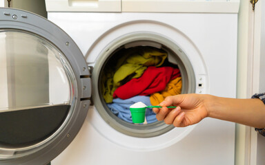 Female hand holds a cap with washing powder.