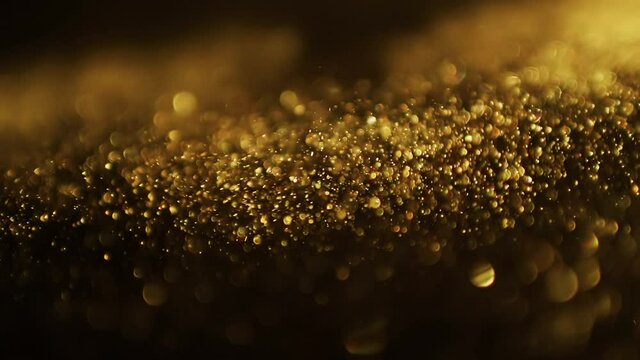 Abstract gold particles in motion over dark background
