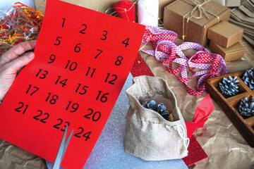 Women's hands cut the numbers for the advent calendar, on the table there are gift packages and a...