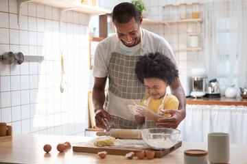 African American boy enjoy cooking with his father in kitchen together. Black Family doing bakery.