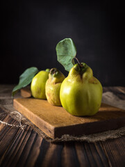 Quince (Cydonia oblonga) with leaves on a wooden board. Free space for text
