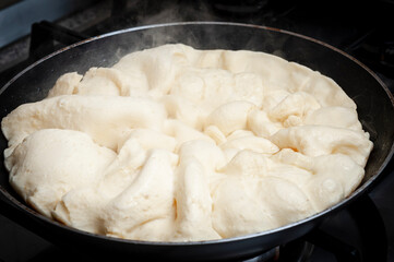 Raw dough of kaiserschmarrn during cooking in a metal pan on the oven