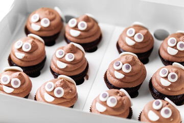 Set of cupcakes in the white gift box. Chocolate cupcake with brown cream cheese top decorated with mastic smiley face