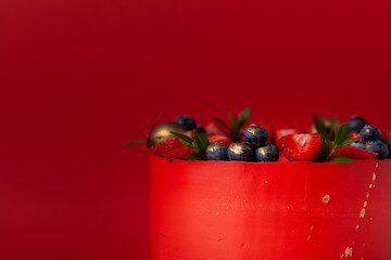 Red cake with cream cheese frosting for a big event. luxurious cake with golden decoration and berries on top on the red background