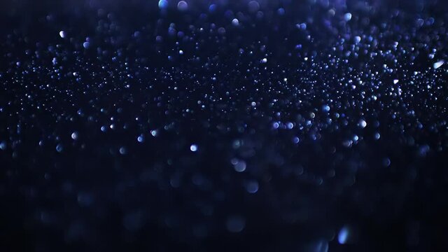 Blue sparkle particles with bokeh effect, abstract background