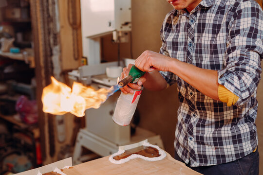 Carpenter lighting a blowtorch in a workshop