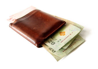 Several Thai banknotes in a brown wallet placed on a white background.