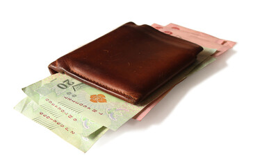 Several Thai banknotes in a brown wallet placed on a white background. Isolated.