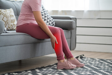 The woman's calf muscle cramped, massage of female leg in home interior