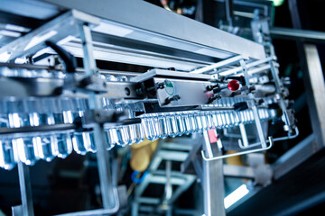 Fototapeta premium Automatic filling machine pours water into plastic PET bottles at modern beverage plant.