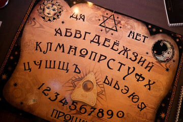 Mystic ritual with Ouija and candles. Devil's board concept, black magic or fortune telling rite...