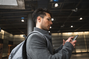 Casual urban professional businessman wearing backpack using his cell phone