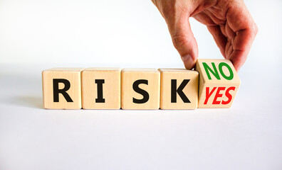 Question about Risk symbol. Businessman turns a wooden cube and changes words 'risk yes' to 'risk no'. Beautiful white table, white background, copy space. Business risk yes or no concept.