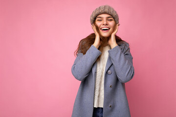 Attractive smiling happy young brunet woman standing isolated over colorful background wall wearing everyday stylish outfit showing facial emotions looking at camera