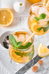 Traditional iced tea with lemon and ice in tall glasses on marble table background Iced tea with lemon. Selective focus. Refreshment cold summer drink.