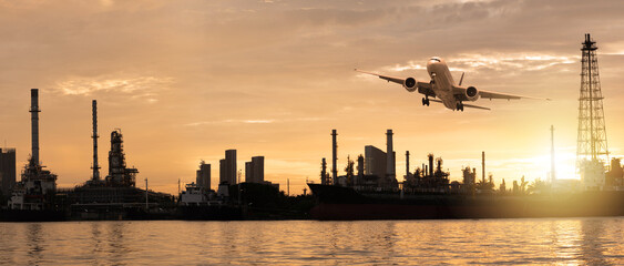 View of airplane flying, oil refinery industry plant and river at sunset as transportation, energy...