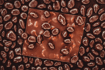 Bitter dark chocolate bar and chocolate dragee with nuts close-up, top view