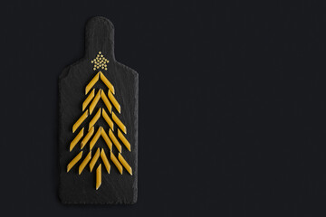 christmas tree made of pasta penne on black board background. new year 2022 from food. holiday...