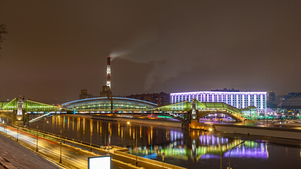 View of the colorful Bogdan Khmelnitsky bridge illuminated at night reflecting in the Moskova river. Moscow, Russia
